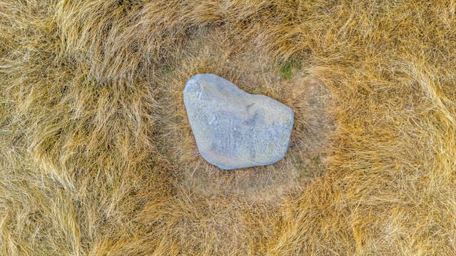 An aerial view hovering above  the Judith Stone, a large glacial erratic block located in a ridge and furrow field in Lubenham, Leicestershire in summertime