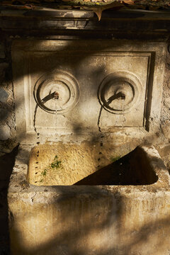 View of an old stone fountain with two spouts flowing into a basin in Andalusia, Spain.