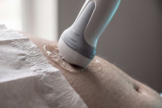 Doctor performing an abdominal ultrasound scan on a patient with a medical transducer and gel