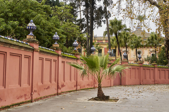 View of the historic pink walls and ornate ceramic finials of the Real Alcazar in Seville, Andalusia, Spain.