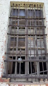 A massive, rusted iron grille on the window of an old brick building.