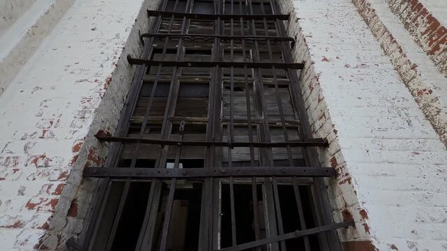 A massive, rusted iron grille on the window of an old brick building.