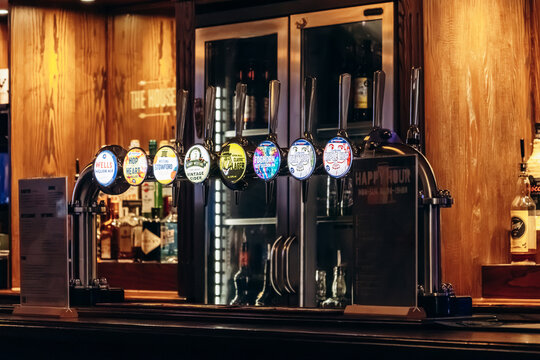 Bordeaux, France - July 14, 2026: Selection of draft beers and ciders on tap inside a pub in central Bordeaux, with branded tap handles displayed above the bar counter.