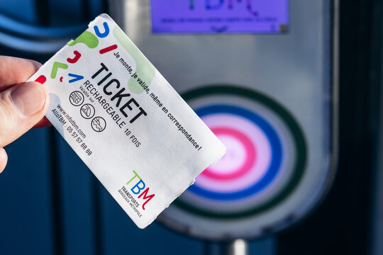 Bordeaux, France - July 14, 2026: A man holds a rechargeable TBM public transport ticket next to a contactless validator inside a Bordeaux tram. 