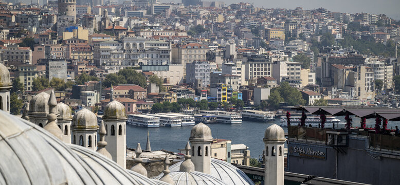 View of the Golden Horn in Istanbul, featuring historic mosque domes, passenger ferries on the water, and the dense urban skyline with the Galata Tower, Istanbul, Istanbul, Turkiye.