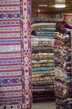 View of stacks of colorful, intricately patterned traditional Turkish carpets displayed in a shop in Istanbul, Istanbul, Turkiye.