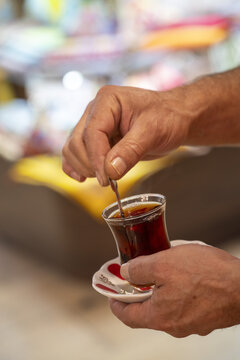 View of a person stirring a glass of traditional Turkish tea with a small spoon in Istanbul, Istanbul, Turkiye.