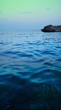 Blue sea water waves abstract background nature surface. This serene water view captures calm liquid motion along a rocky shoreline in Europe, creating a minimal texture