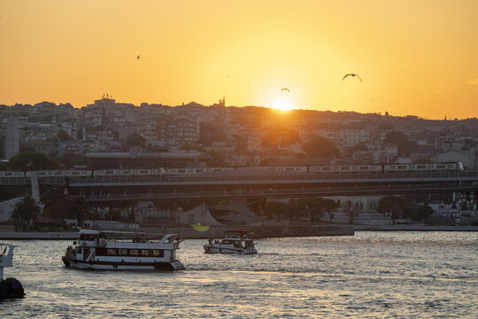 View of boats sailing on the Bosphorus during a golden sunset with the city skyline and a bridge in the background in Istanbul, Istanbul, Turkiye.