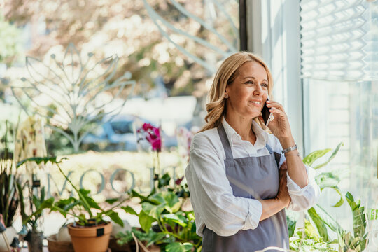 Female florist entrepreneur talking on phone in shop