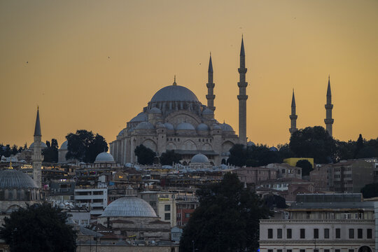 View of the Suleymaniye Mosque with its iconic domes and minarets silhouetted against a warm golden hour sky over the historic cityscape of Istanbul, Istanbul, Turkiye.