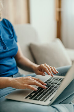 Woman's hands typing on laptop keyboard at home