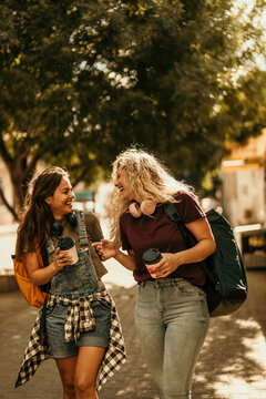 Happy young female friends laughing walking outdoors