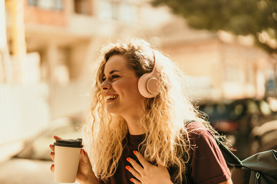 Happy woman listening to music and drinking coffee