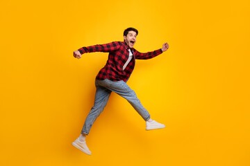 Fototapeta premium Excited Young Caucasian Man Jumping With Joy, Showing Enthusiasm And Energy, Positioned Against Bright Yellow Background. Perfect For Lifestyle And Happiness Concept.
