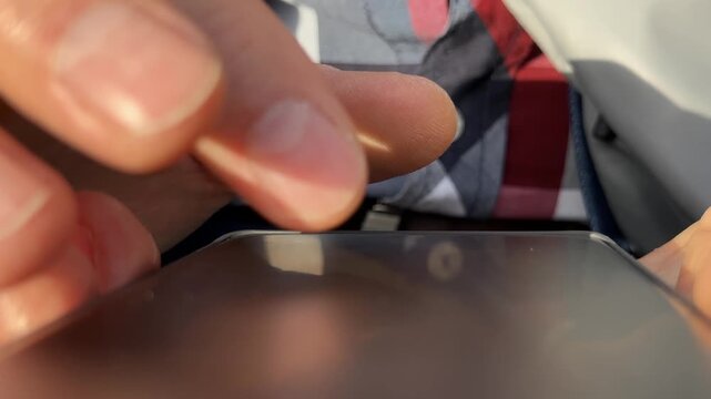 Close up of thumb finger scrolling social media content on smartphone screen. Macro view of mature person sliding through digital application feed lines. Mobile interface interaction concept