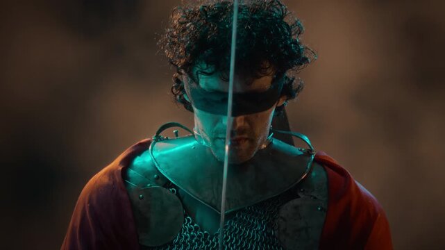 Blindfolded Caucasian young adult man wearing knight armor wielding glowing fantasy sword. Ideal for medieval video game trailers, fantasy storytelling, and entertainment advertising