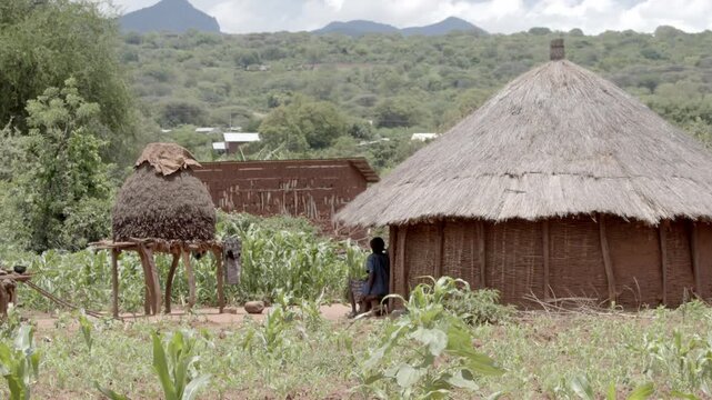 A woman sits in front of a traditional grass hut in a Banna tribal village in Southern Ethiopia, slow motion shot.