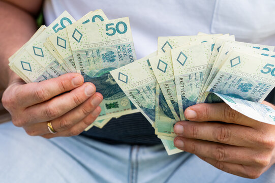 Male Hands Fan Out Polish Zloty Currency Banknotes Stack for Financial Success and Savings