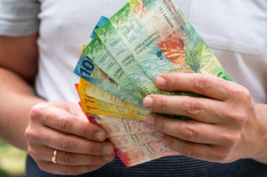 Close up of Man Hands Holding Fan of Swiss Franc Currency Notes for Financial Wealth Concept