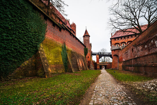 Malbork, Pomeranian Voivodeship, Poland - 23 March 2026: View of Malbork Castle with red brick walls, defensive towers, and a stone path leading through the historic fortress.