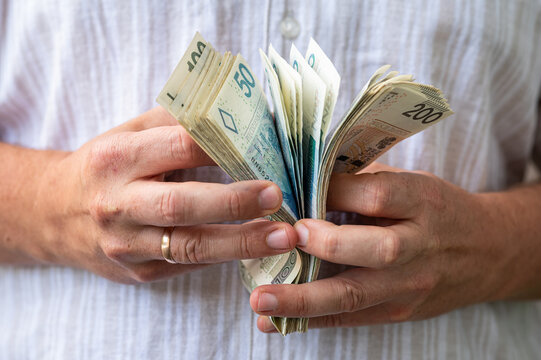 Close up of Man Hands Holding Fan of Polish Zloty Banknotes for Income and Savings Concept