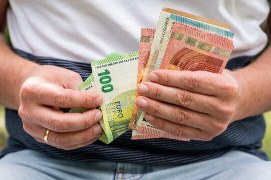 Male Hands Holding and Counting Stack of 100 Euro Currency Bills for Business Finance Concept