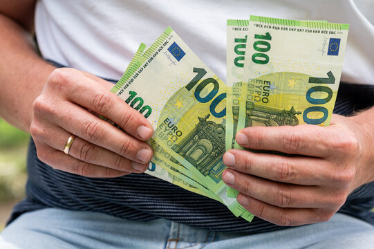 Male Hands Holding and Counting Stack of 100 Euro Currency Bills for Business Finance Concept
