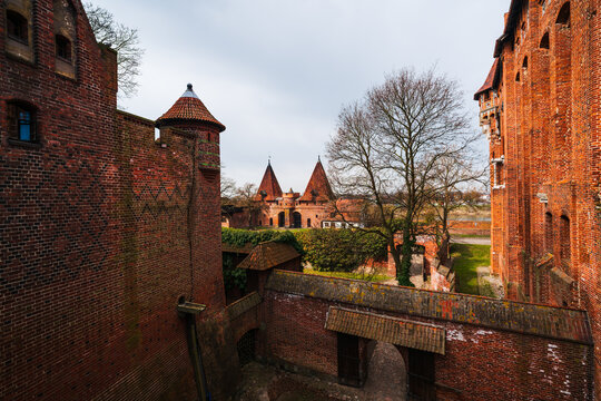 Malbork, Pomeranian Voivodeship, Poland - 23 March 2026: View of the historic red brick fortifications and towers of Malbork Castle under a cloudy sky.