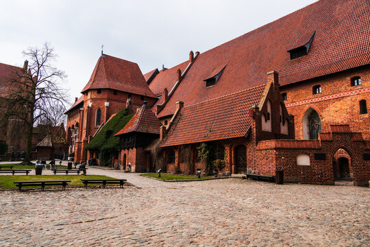 Malbork, Pomeranian Voivodeship, Poland - 23 March 2026: View of the historic Malbork Castle with red brick Gothic architecture, steep tiled roofs, and a cobblestone courtyard.