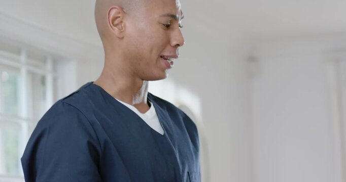 Senior Asian woman adjusting cardigan on African American aide in scrubs speaking, helping at home