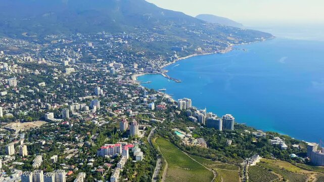 Yalta, Crimea. Panorama of the city in sunny weather. Embankment and port. Drone footage