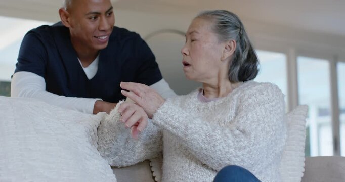 Caregiver in navy scrubs seeing senior Chinese woman unsure, leaning, holding hand