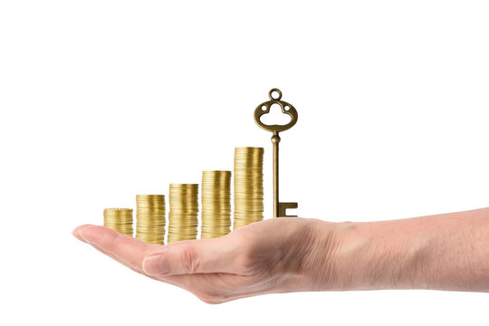 Hand holding stacks of gold coins forming a graph and a golden key to success