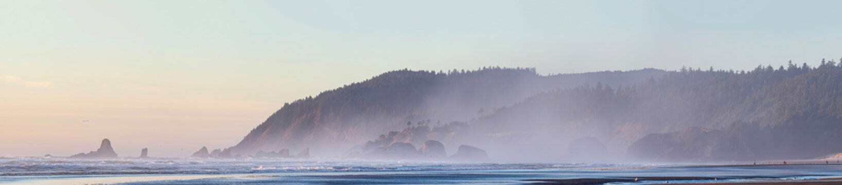 Beautiful wide panoramic view of a wild ocean coast with misty forested mountains and sea stacks