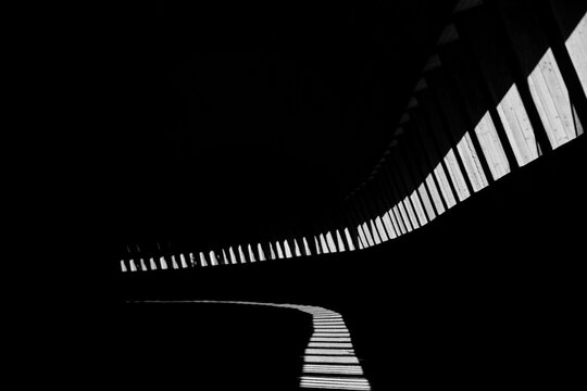 Abstract light and shadow pattern inside a dark curved corridor.