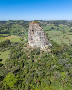 Aerial view of Torre de Pedra rock formation surrounded by green hills