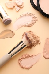 Obraz premium Swatches of different foundations, face powders and brushes on beige background, flat lay