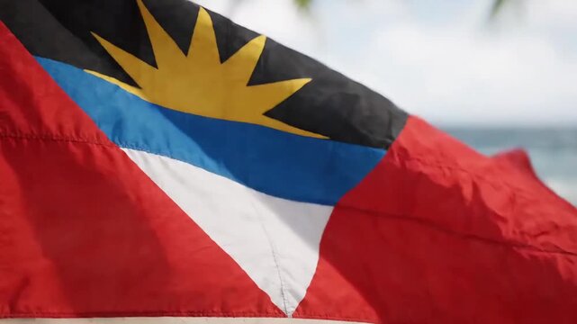 Antigua flag waving on a tropical beach with ocean background