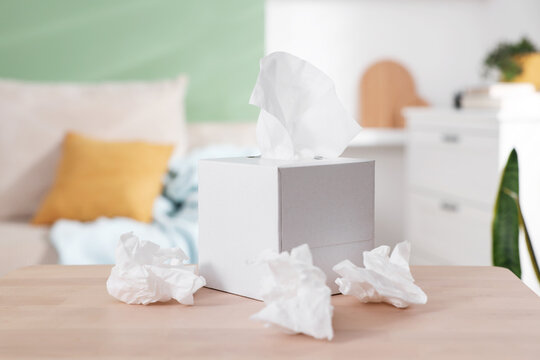 Box of paper tissues and used napkins on table indoors