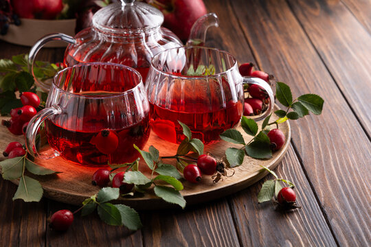 Warm Rosehip Tea Served in Glass Cups with Fresh Berries and Leaves on Wooden Table