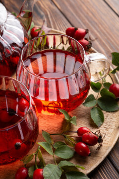 Warm Rosehip Tea Brewed in Glass Cups and Teapot with Fresh Berries on Wooden Tray