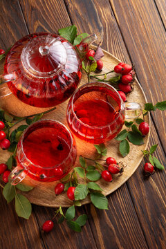Warm Rosehip Tea served in Glass Teapot and Cups on Wooden Table Rustic Ambiance