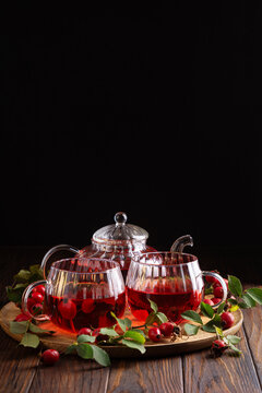 Rosehip tea set for two with fresh berries and leaves on a wooden tray