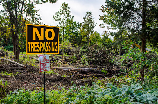 No Trespassing sign in the foreground of a woodlot clear cut project