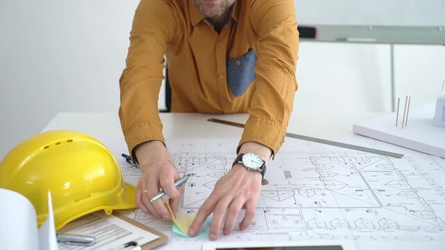 Architect or engineer working on architectural blueprints, drawing construction plans, designing a building project, and planning future development in an office