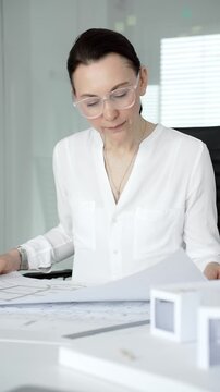 Professional female architect working on detailed construction plans and engineering drawings, utilizing tools and expertise for urban development and design projects