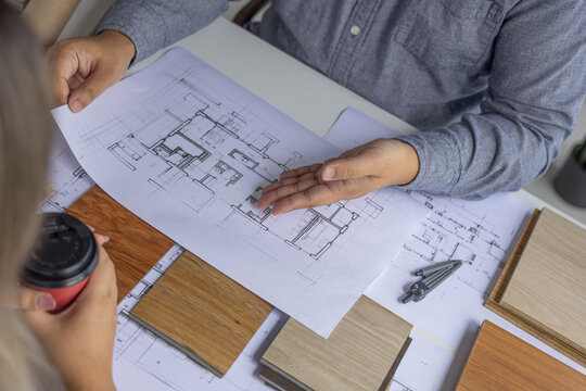 An architect or interior designer is reviewing floor plans with a client to finalize design details.