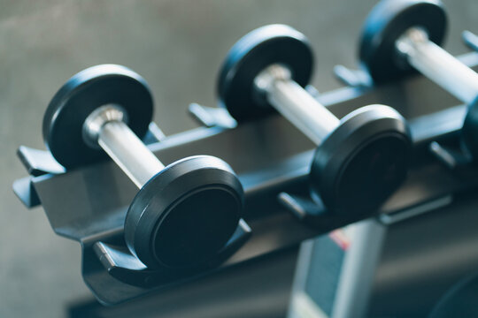 Dumbbell weight equipment arranged on metal rack in modern gym, ready for strength training and muscle building with focused fitness energy