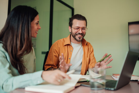 Diverse business team actively engaging in a meeting, sharing ideas and smiling in a contemporary office workspace